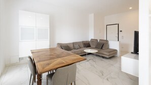 Ein modernes Wohnzimmer mit einem Holzespeisetisch, einem grauen Sofa und einem weißen Couchtisch.