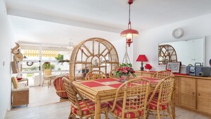 A dining area with a red and white checkered tablecloth, wicker chairs, and a hanging light fixture.