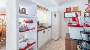 A compact kitchen with white cabinets, a wooden countertop, and a coffee machine.