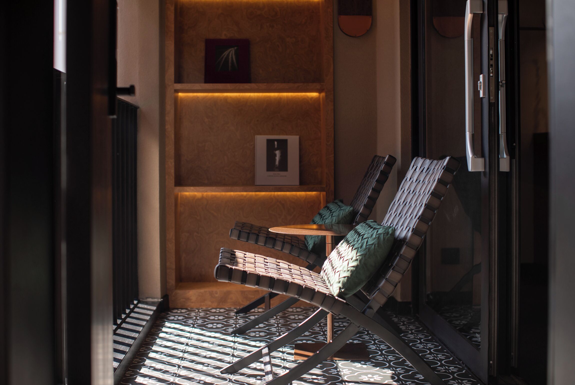 A modern lounge area with a reclining chair, a small table, and a patterned floor.