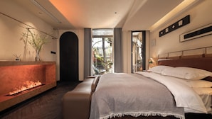 Ein modernes Schlafzimmer mit Kamin, einem großen Bett und Gartenblick durch eine Glastür.
