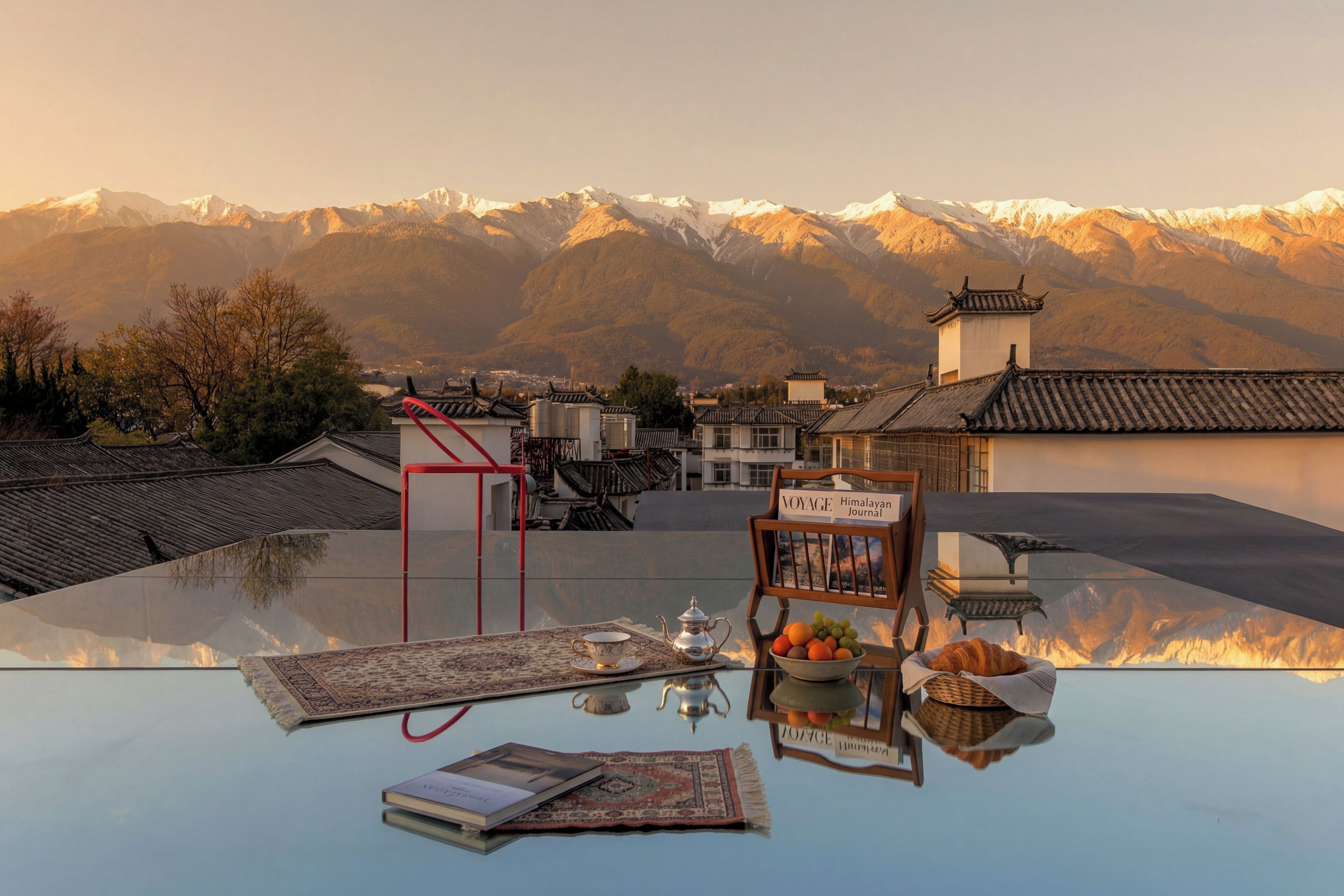 Une table avec vue sur les montagnes, un livre, une théière et un bol de fruits.