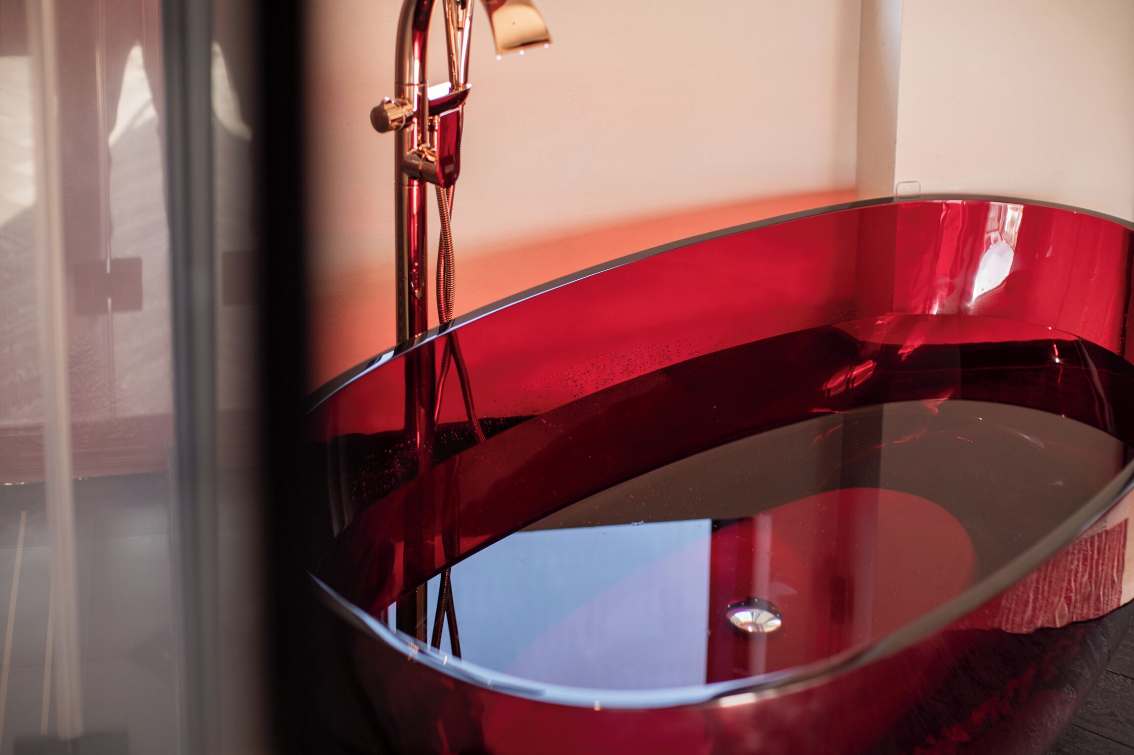 A modern bathroom with a glass bathtub and a chrome faucet.