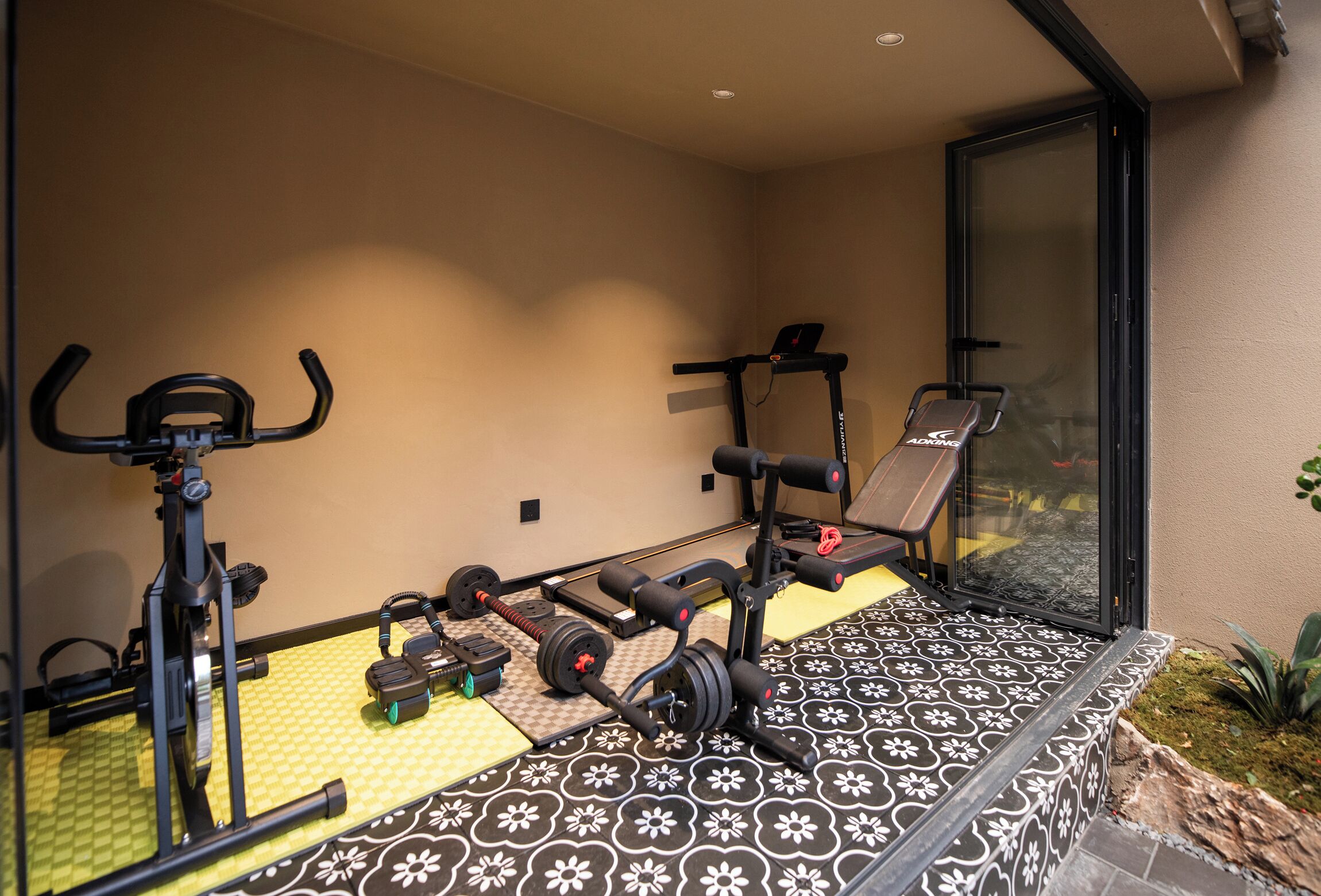 A home gym with exercise equipment, including a treadmill, weight bench, and dumbbells.