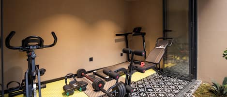 A home gym with exercise equipment, including a treadmill, weight bench, and dumbbells.