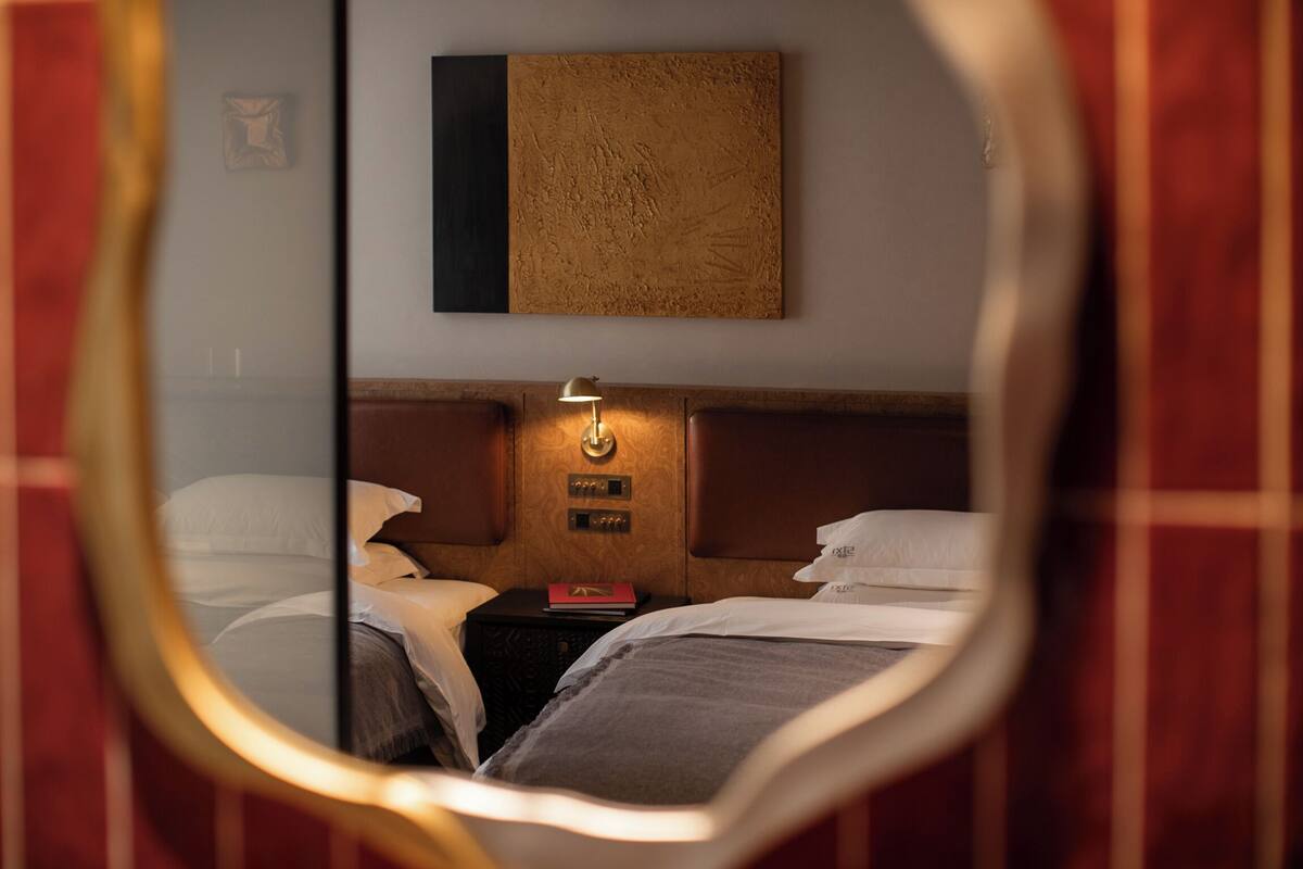 Quarto de hotel com cama, mesa de cabeceira, luminária e uma obra de arte pendurada na parede.