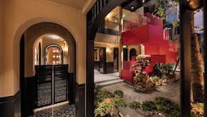 Eine Hotelhalle mit modernem Design, inklusive einem zentralen Innenhof mit Pflanzen und einem roten Gebäude.