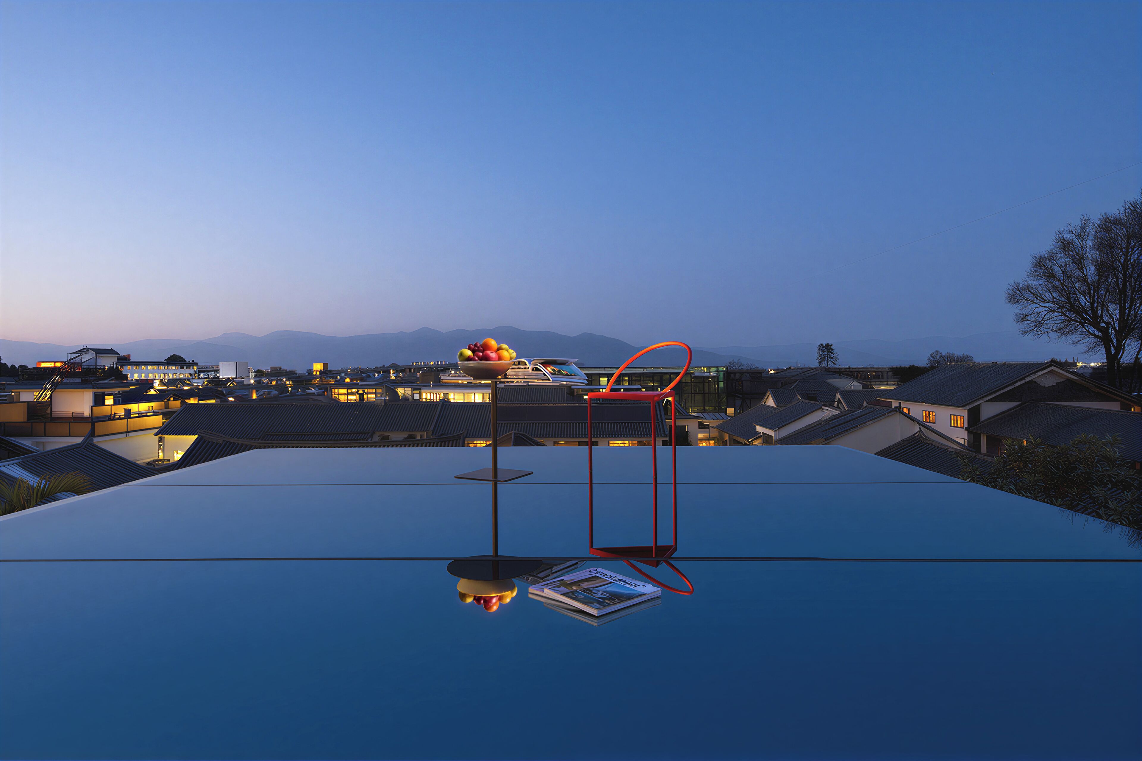 A rooftop with a glass table, a bowl of fruit, and a magazine.