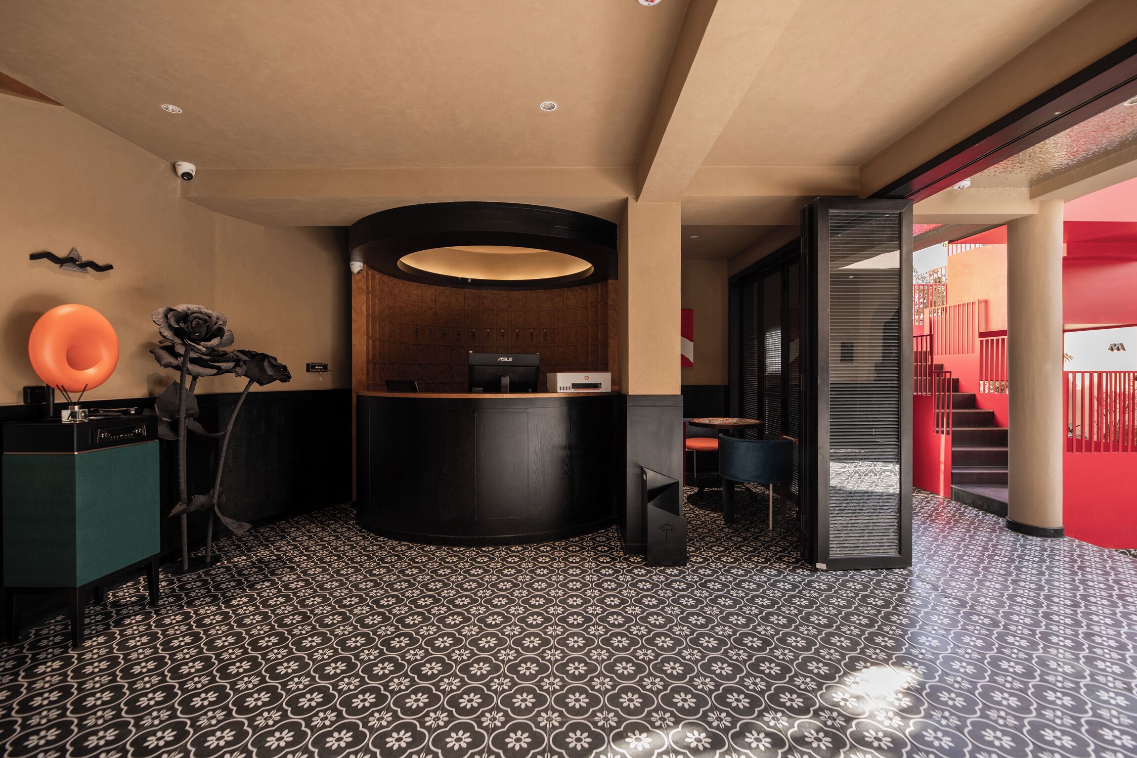 A reception area with a black reception desk, a large circular light fixture, and a patterned floor.
