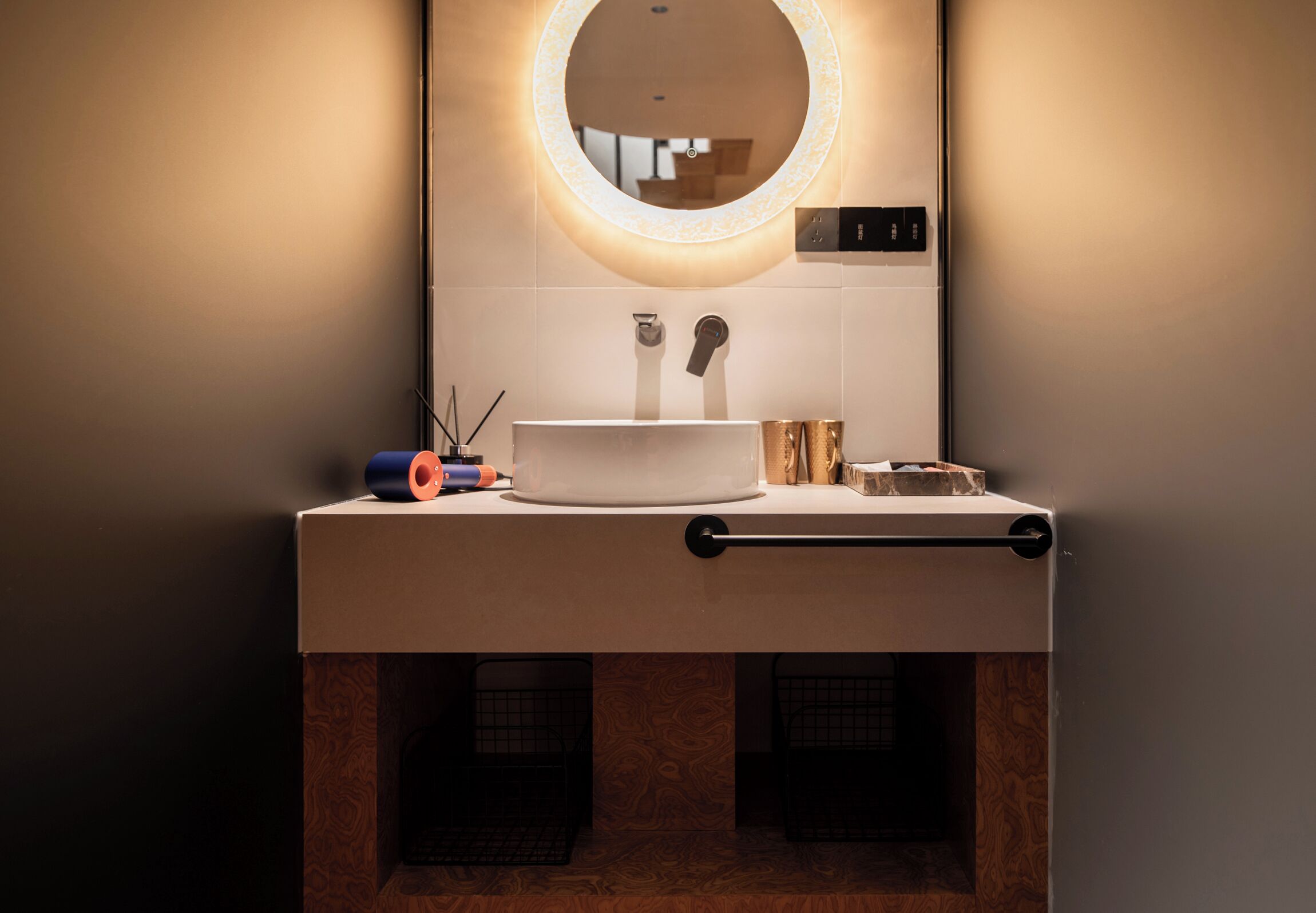 A modern bathroom with a round mirror, a white sink, and a towel rack.