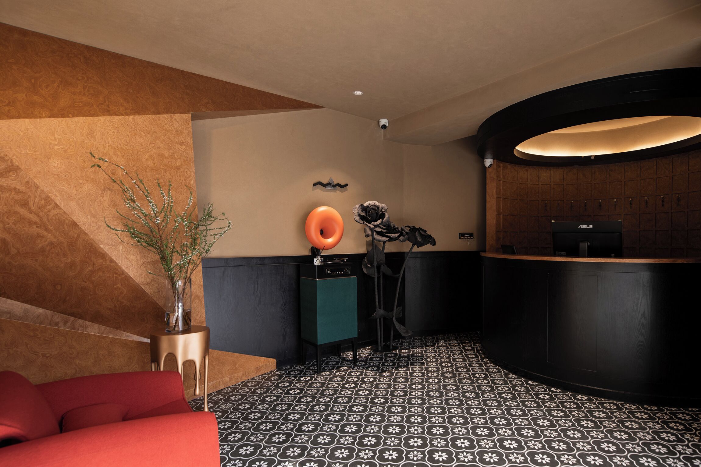 Ein Empfangsbereich mit einer gebogenen Theke, einem roten Sofa, einer dekorativen Vase und einem Fußboden mit Muster.