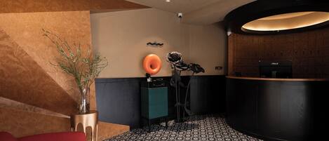 Un área de recepción con un mostrador curvo, un sofá rojo, un jarrón decorativo y un suelo estampado.