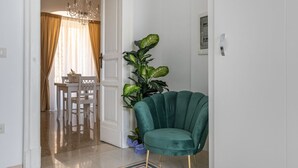 A room with a green armchair, a dining table with chairs, a chandelier, and a large plant. - GuestHost Chic B&B Piazza Libertà - Suite Lecce (Ostuni)