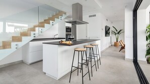 A modern kitchen with a central island, bar stools, a glass staircase, and a large window. - Ca Na Cati (barcarÉs) - Villa With Private Pool (Es Barcarès (alcúdia), Illes Balears)