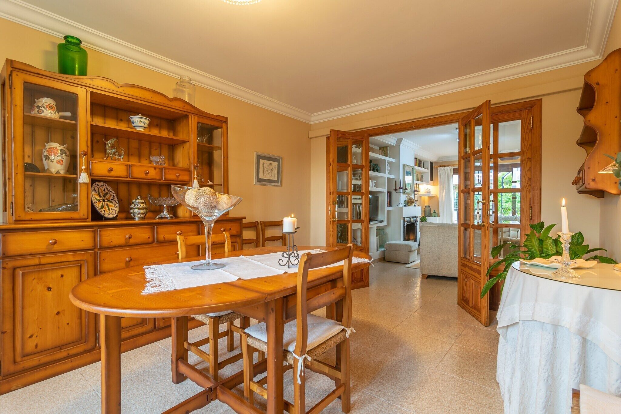A dining area with a wooden table and chairs, surrounded by wooden cabinets with glass doors displaying various items.