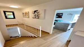 A staircase leading to a modern kitchen area with a dining table and chairs. - Apartments Kalinić (Janjina)
