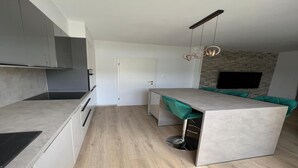 A modern kitchen with grey cabinets, a central island, and a stone accent wall. - Apartments Kalinić (Janjina)