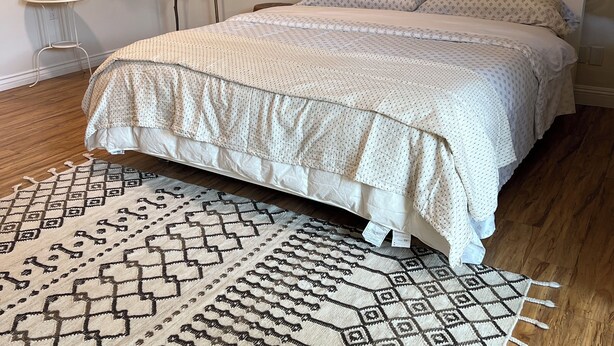 A bedroom with a bed, a patterned rug, a small table, and a plant. - Spacious 5-Master suite house in UC Riverside with individual AC, WiFi. Enjoy! (Riverside)