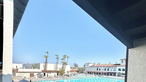 A view of a swimming pool area with multiple lanes, palm trees, and buildings in the background. - Resort Style Home near Beaches & Disneyland (Fountain Valley)