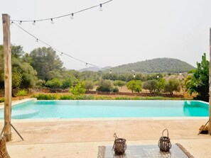 A swimming pool with a view of a hilly landscape, surrounded by greenery. - Villa near Cala Tropicana with Pool (S' Espinagar)