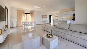 Una sala de estar moderna con un sofá, una mesa de comedor y una zona de cocina al fondo.