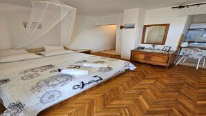 A bedroom with a bed, a wooden herringbone floor, a nightstand, a dresser, a chair, and a mirror. - Studio in Tribunj near Bristak Beach (Tribunj)