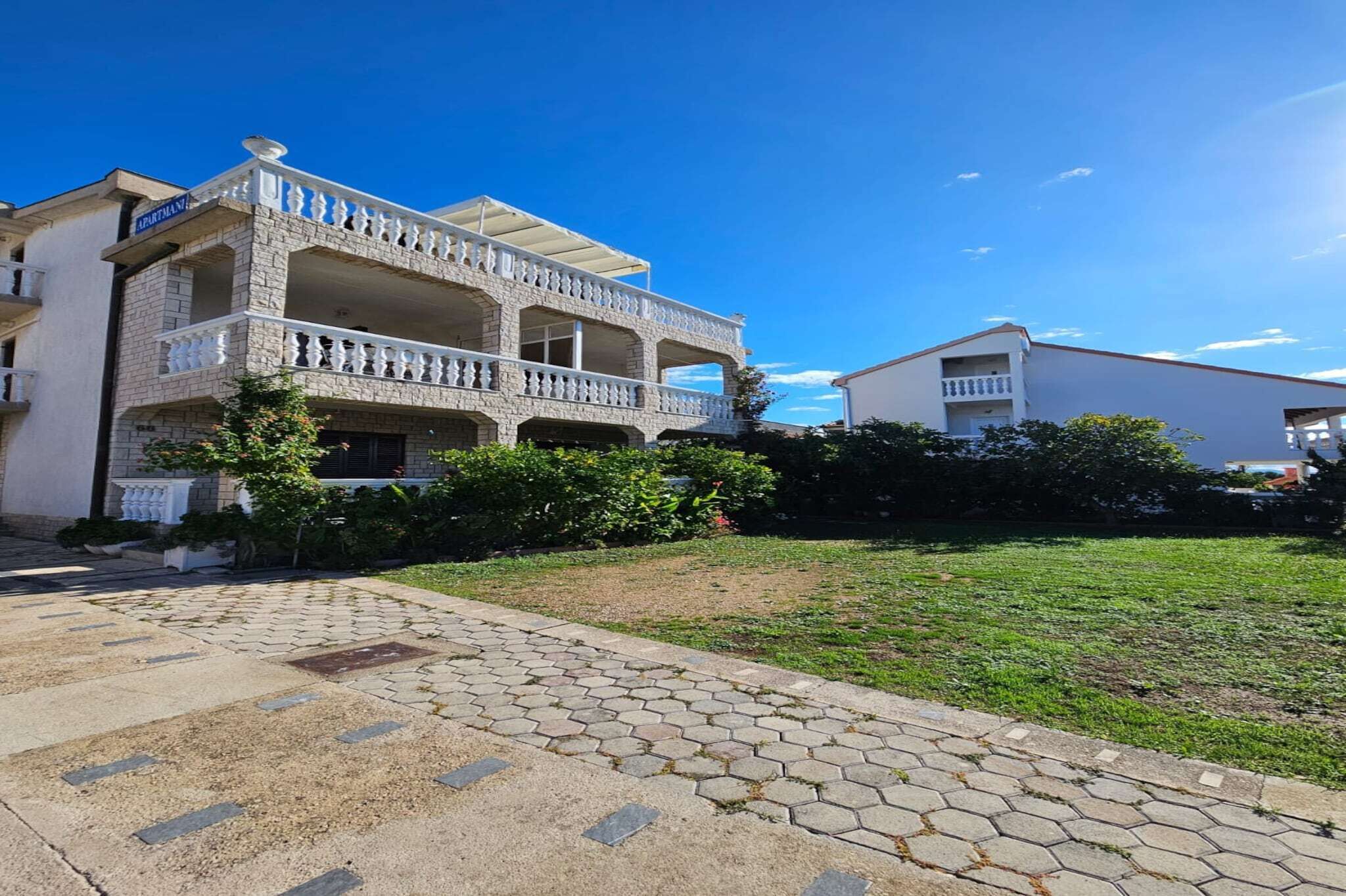 A two-story building with a balcony on the ground floor and a flat roof.