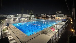 A nighttime swimming pool with lane dividers, a water fountain, and a Ferris wheel. - Resort Style Home near Beaches & Disneyland (Fountain Valley)
