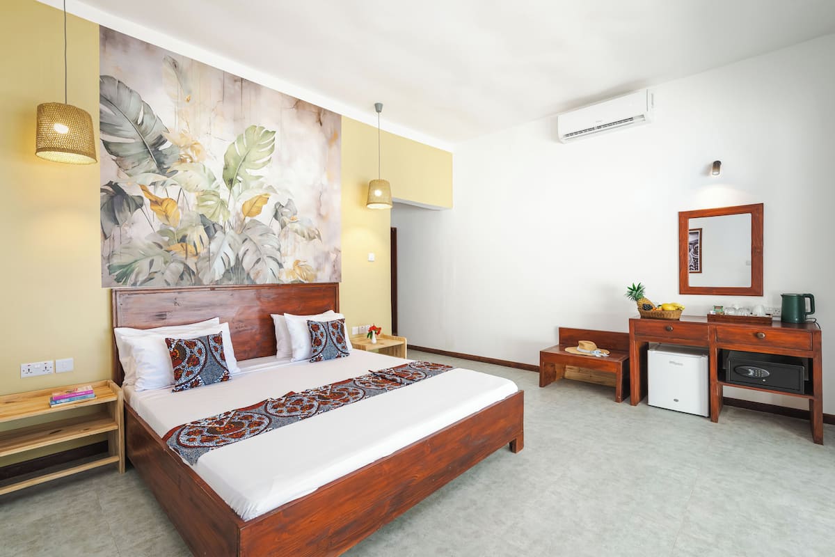 Habitación de hotel con una cama grande, un escritorio, un refrigerador pequeño y un aire acondicionado instalado en la pared.