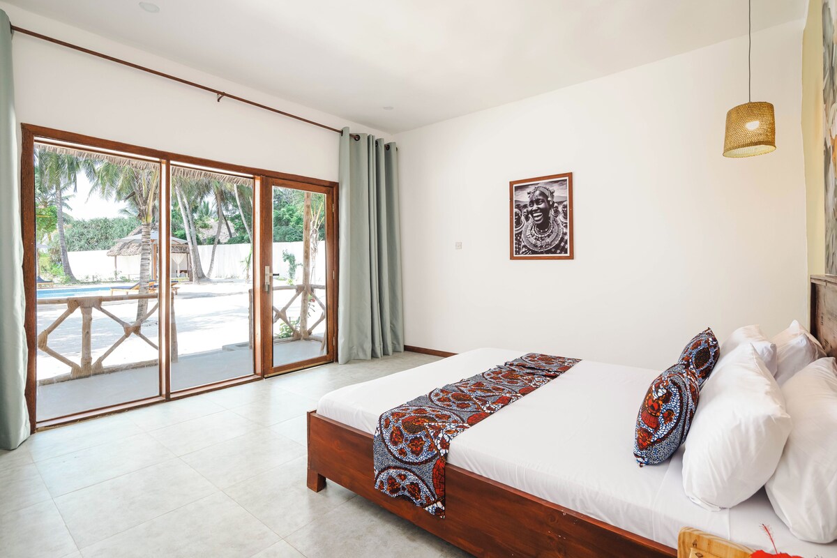 Un dormitorio con cama, una ventana grande y una puerta que da a un espacio exterior.