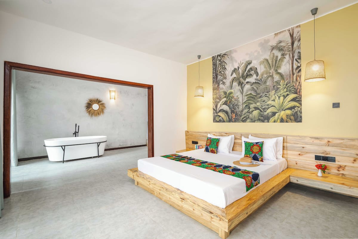 Un dormitorio moderno con una cama grande, una bañera y un mural en la pared.
