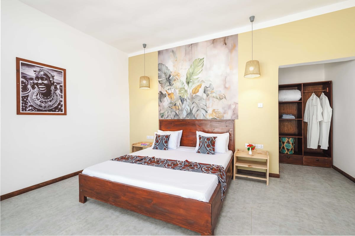 Un dormitorio con una cama de madera, una mesita de noche, una lámpara de pared, un armario y un cuadro enmarcado.