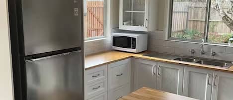Kitchen features a stainless steel refrigerator, microwave, and sink with a faucet, set against a window with a view.