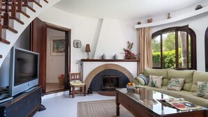A living room with a fireplace, a sofa, a television, and a staircase.