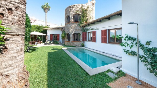 A courtyard with a swimming pool, stone tower, and white walls.