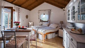 Een gezellige slaapkamer met twee bedden, een houten plafond, een zithoek met een tafel en stoelen, en een raam met gordijnen.