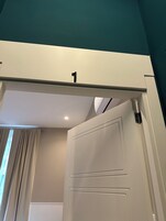 Una stanza con una porta bianca, tende color beige e un soffitto verde acqua.