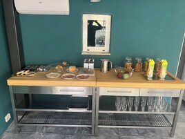 Angolo cottura con fornello, tostapane, bollitore e diversi alimenti sul piano di lavoro.