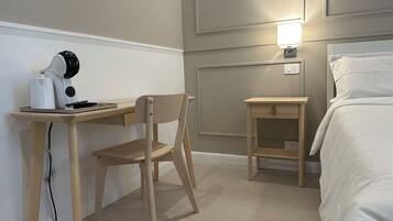 Ein Hotelzimmer mit Holztisch, Stuhl, Nachttisch, Lampe und Bett.