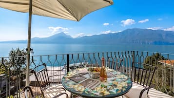 A terrace with a table set for two, overlooking a lake and mountains.