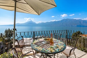 Une terrasse avec une table dressée pour deux personnes, offrant une vue sur un lac et des montagnes.