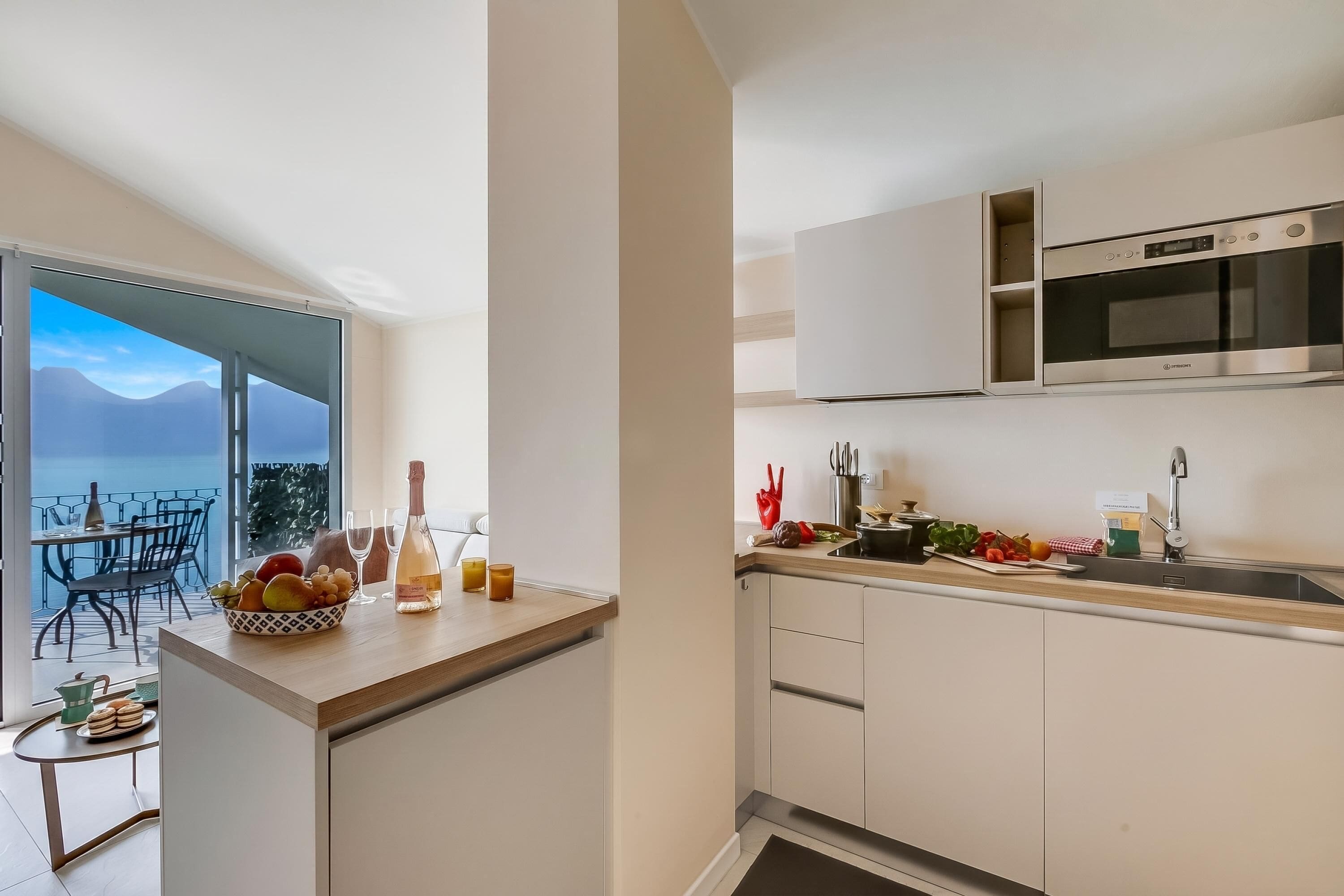 A modern kitchen with a built-in microwave, a sink, and a dining area with a view of the sea.