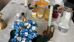 A table set with various dishes, including bread, fruits, and condiments, in a room with blue walls and a patterned tablecloth. - For group 🌟 (Saint-Cyr-en-Pail)