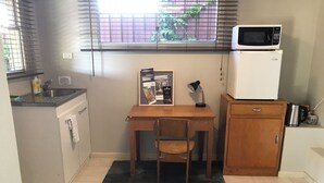 A compact kitchen with a wooden table, a chair, a microwave, and a refrigerator.
