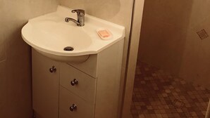 A bathroom with a white sink, a mirror, and a glass shelf.