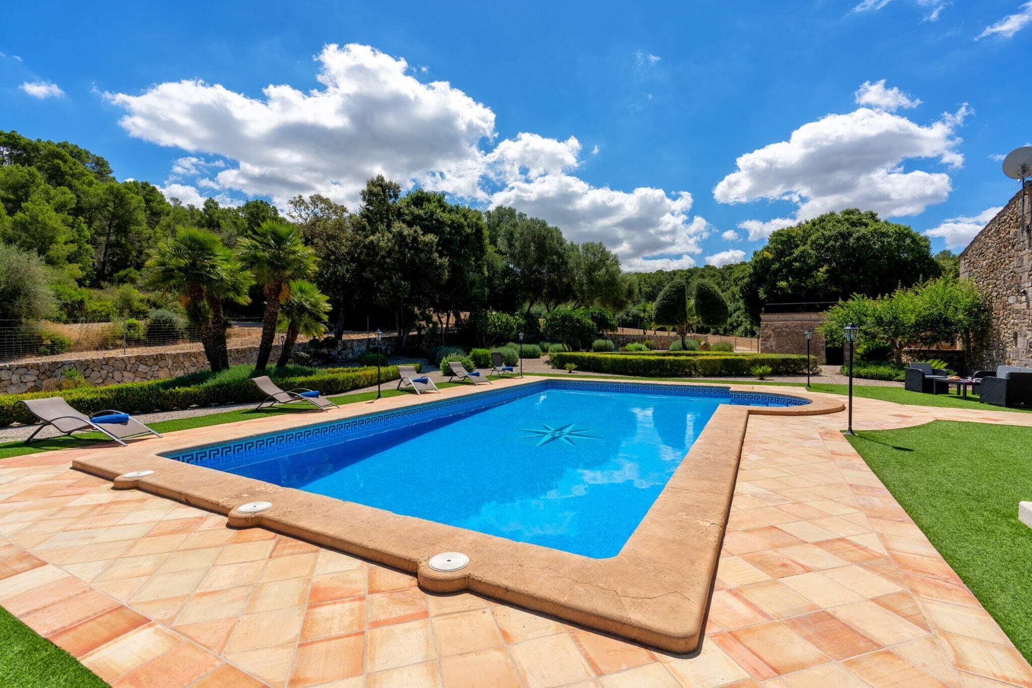 A rectangular swimming pool with a star-shaped design in the center, surrounded by a tiled deck.