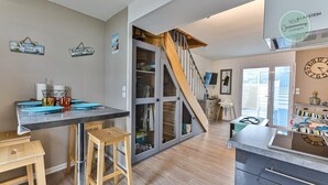 Une cuisine moderne avec un escalier en bois, un coin repas doté de tabourets de bar et un îlot central.