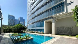 A modern hotel with a rooftop pool, surrounded by a wooden deck and greenery. - Uptown Parksuites Tower Two (Taguig)