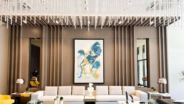 A modern living room with a large sofa set, a coffee table, and a painting on the wall. - Uptown Parksuites Tower Two (Taguig)