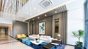 A modern lobby with a reception desk, seating area, and a large window. - Uptown Parksuites Tower Two (Taguig)